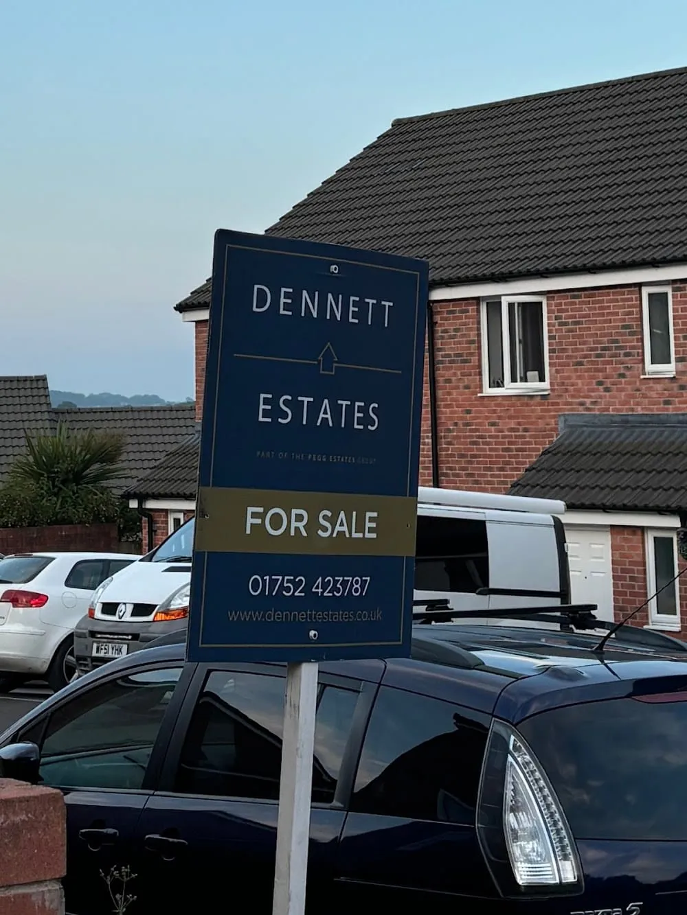A Dennett Estates For Sale board outside a red-brick house